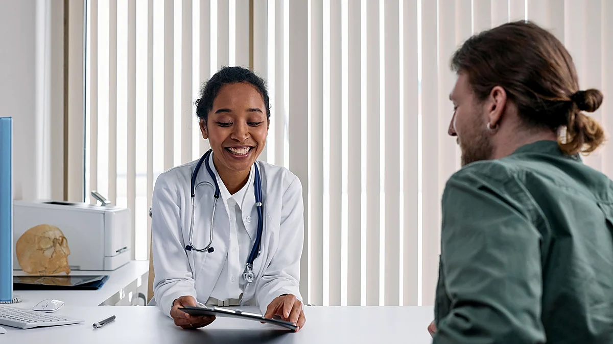 Male patient discussing a new symptom with a doctor in a private consultation